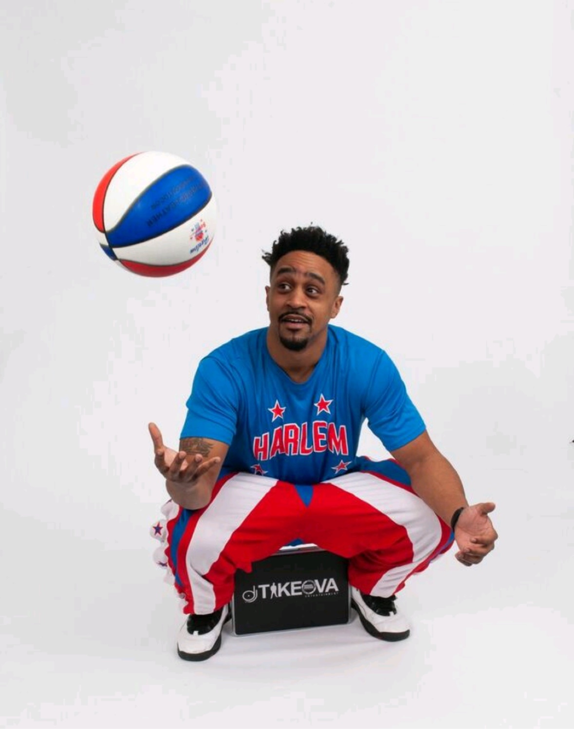 DJ Takeova in a Harlem basketball uniform holding a basketball and his Takeova case