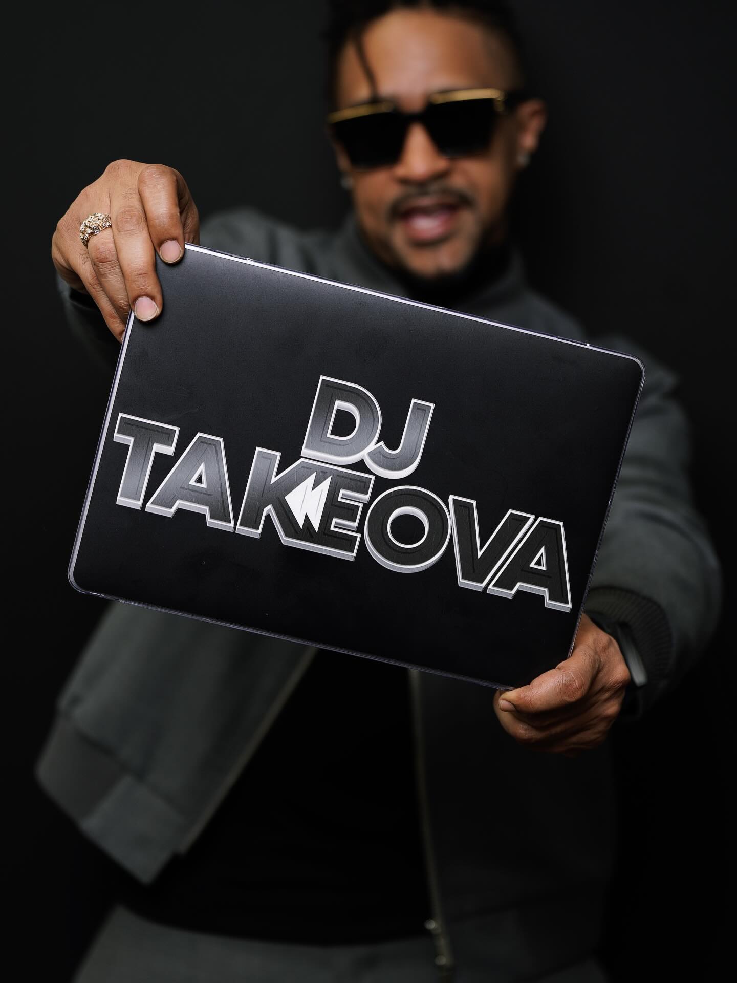 DJ Takeova holding his branded laptop during a portrait session