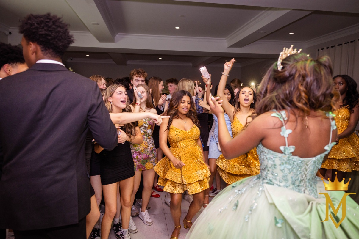Friends in gold dresses dancing around the guest of honor at a sweet 16