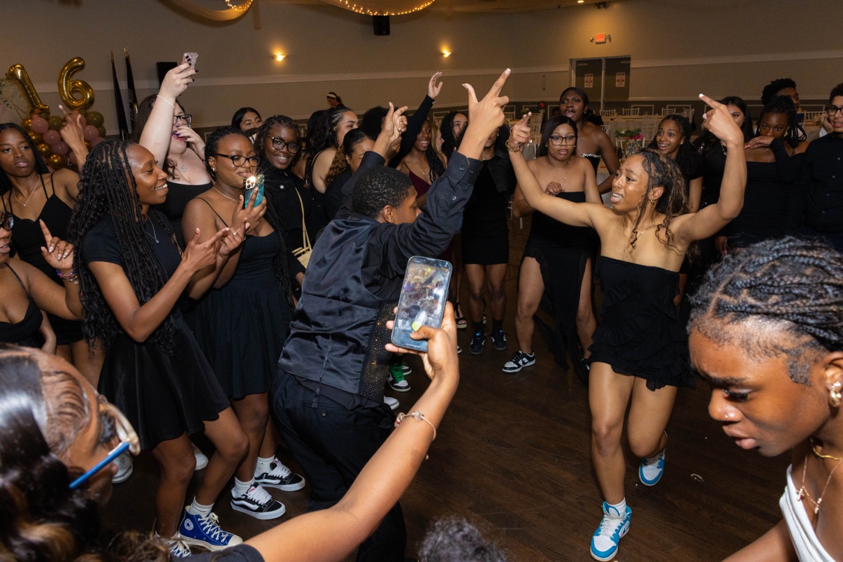 Friends circle up for a dance-off at a sweet 16, phones out and hands in the air