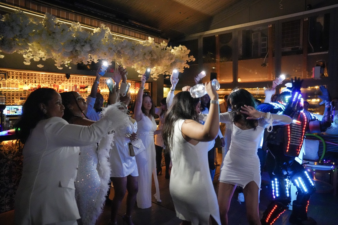 Guests dressed in white dancing with an LED performer at an upscale private party